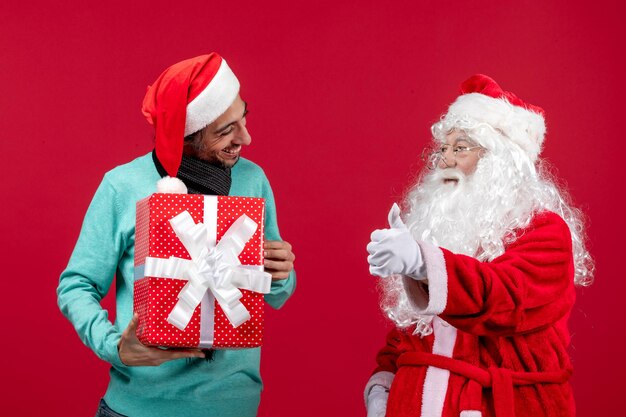 Vista frontal de santa claus con hombre sosteniendo presente de vacaciones en rojo emoción regalo rojo navidad año nuevo