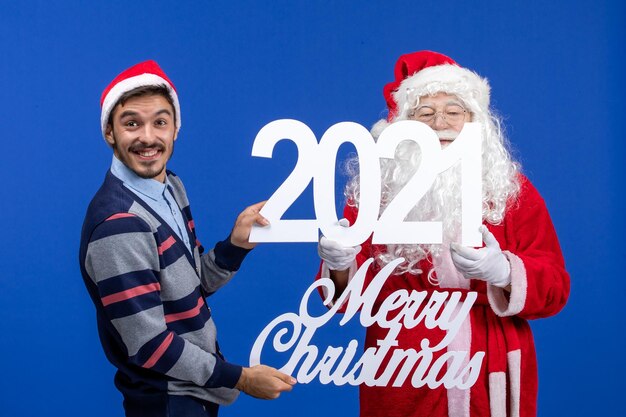 Vista frontal de santa claus con hombres jóvenes sosteniendo y feliz navidad escritos