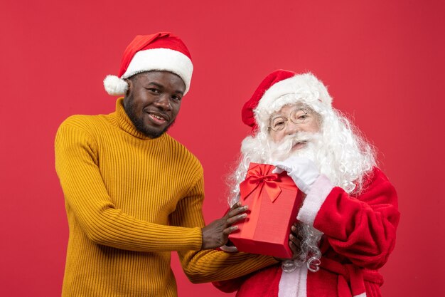 Vista frontal de santa claus con joven en la pared roja