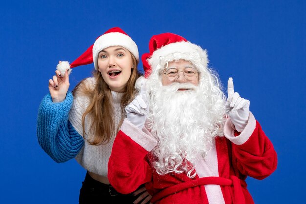 Vista frontal de santa claus junto con la mujer joven en las vacaciones de año nuevo de color azul navideño humano