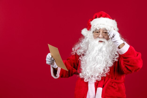 Vista frontal santa claus leyendo la carta de un niño en la emoción de vacaciones de navidad roja