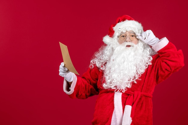 Vista frontal santa claus leyendo la carta de un niño en las emociones de vacaciones de navidad rojas