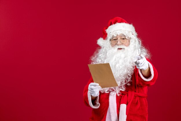 Vista frontal santa claus leyendo carta de niño en rojo emoción presente vacaciones de navidad