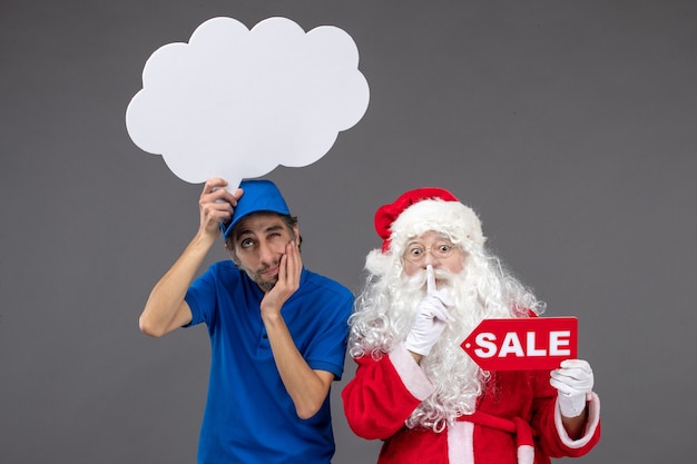 Vista frontal de santa claus con mensajero masculino con cartel de nube blanca y venta en pared gris