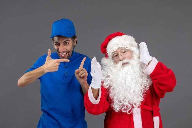 Vista frontal de santa claus con mensajero masculino en la pared gris