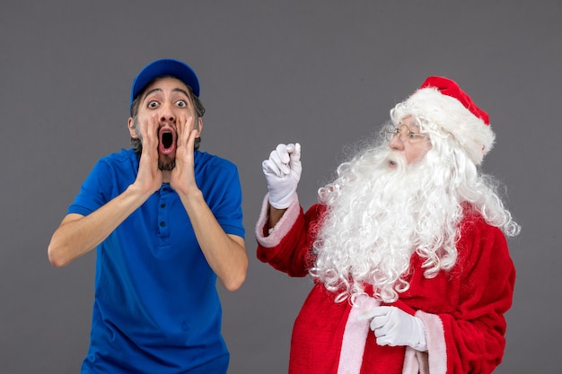 Vista frontal de santa claus con mensajero masculino en la pared gris