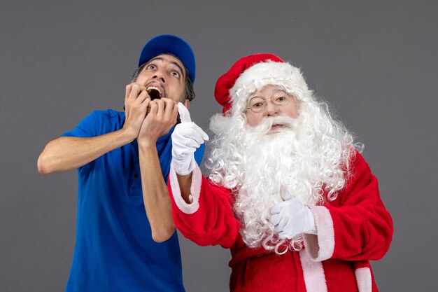 Vista frontal de santa claus con mensajero masculino en la pared gris