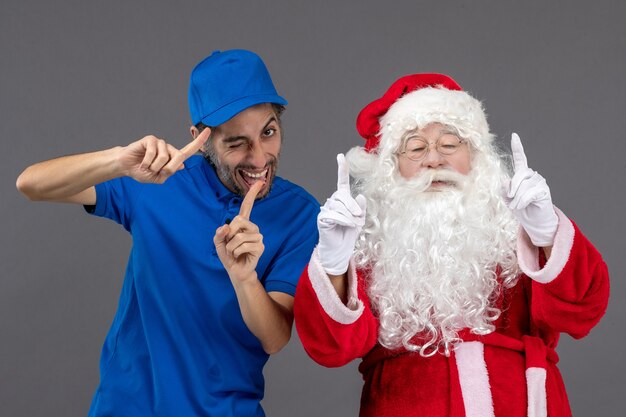 Vista frontal de santa claus con mensajero masculino en la pared gris