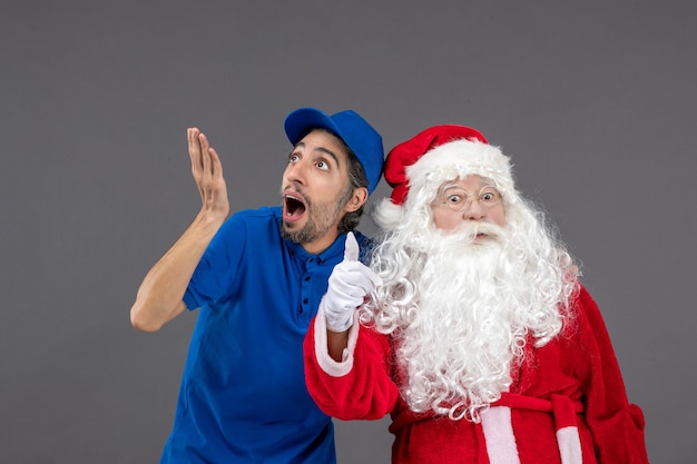 Vista frontal de santa claus con mensajero masculino en la pared gris