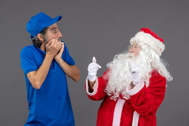 Foto gratuita vista frontal de santa claus con mensajero masculino en la pared gris