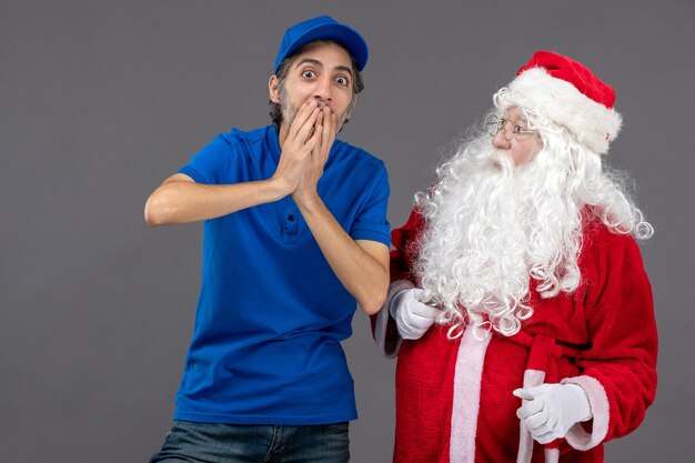 Vista frontal de santa claus con mensajero masculino en la pared gris