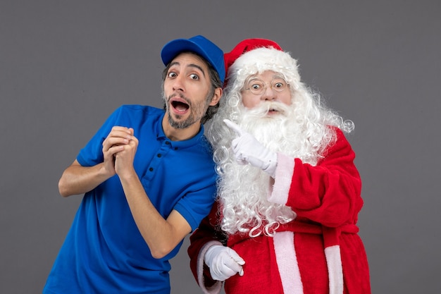 Foto gratuita vista frontal de santa claus con mensajero masculino en la pared gris