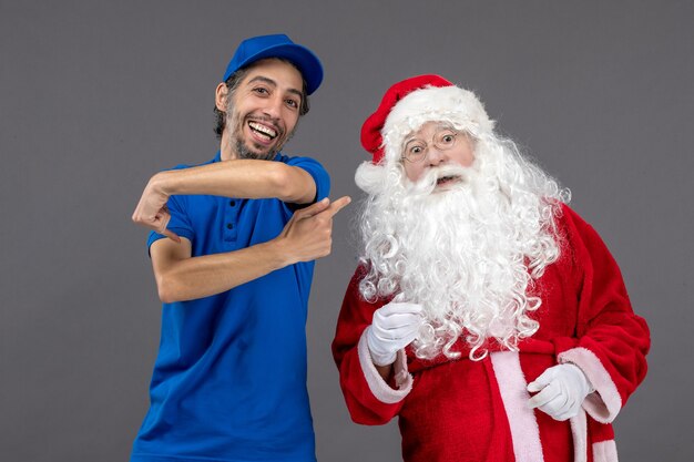 Foto gratuita vista frontal de santa claus con mensajero masculino en la pared gris