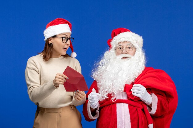 Vista frontal santa claus y mujer joven carta de apertura en azul vacaciones emoción navidad año nuevo