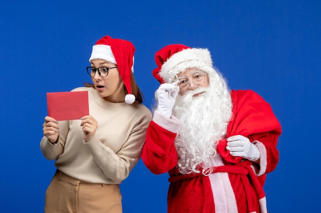 Vista frontal de santa claus y mujer joven con letra en una emoción de vacaciones azul navidad año nuevo