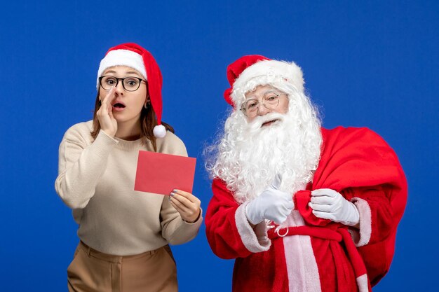 Vista frontal de santa claus y mujer joven sosteniendo una carta en azul vacaciones navidad año nuevo color emoción