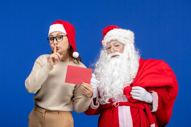 Vista frontal de santa claus y mujer joven sosteniendo una carta en color azul vacaciones navidad año nuevo emociones de color