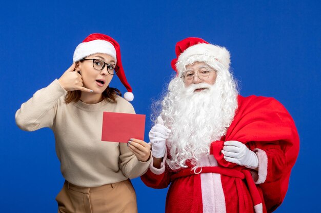 Vista frontal de santa claus y mujer joven sosteniendo una carta en vacaciones azules navidad año nuevo color emoción
