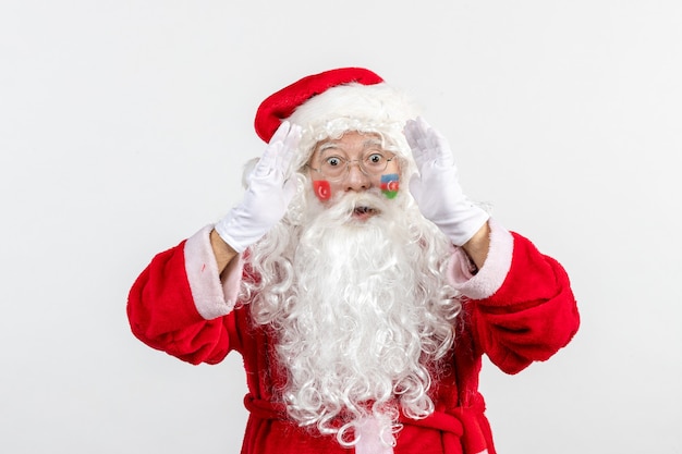 Vista frontal de santa claus con pinturas de la bandera turca y azerbaiyana en su rostro en la pared blanca