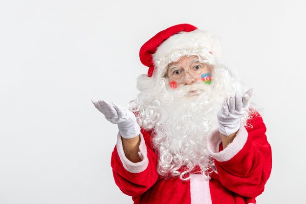 Vista frontal de santa claus con pinturas de la bandera turca y azerbaiyana en su rostro en la pared blanca