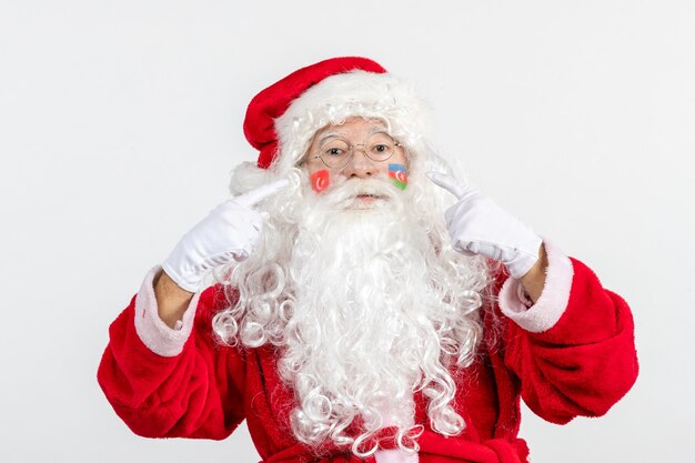 Vista frontal de santa claus con pinturas de la bandera turca y azerbaiyana en su rostro en la pared blanca