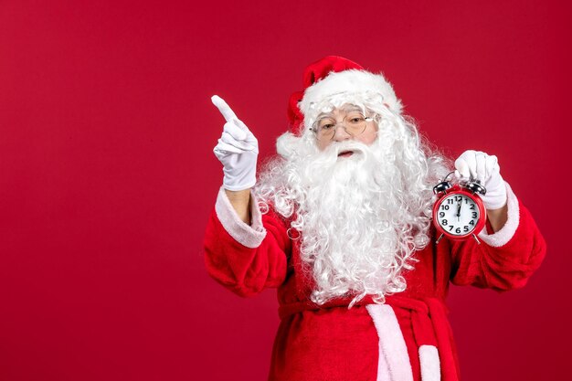 Vista frontal de santa claus con reloj en rojo navidad emoción vacaciones año nuevo