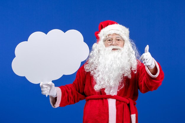 Vista frontal de santa claus sosteniendo un gran cartel en forma de nube en la nieve azul color navideño