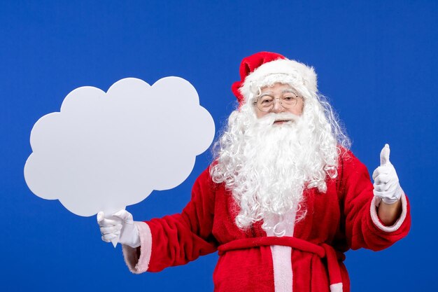 Vista frontal de santa claus sosteniendo un gran cartel en forma de nube en las vacaciones de navidad de color azul nieve