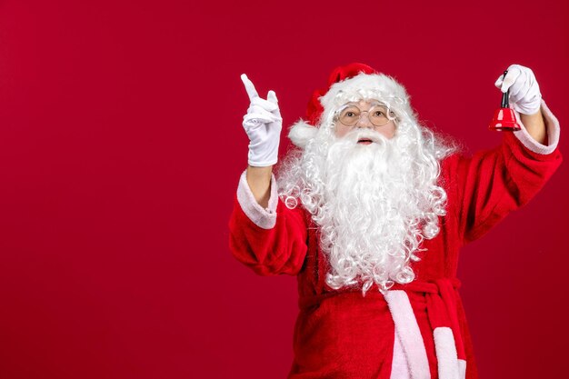 Vista frontal de santa claus sosteniendo una pequeña campana en la emoción de regalo rojo vacaciones de año nuevo de navidad