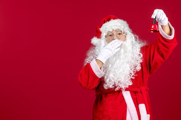 Vista frontal de santa claus sosteniendo una pequeña campana en regalo rojo emoción vacaciones de navidad año nuevo