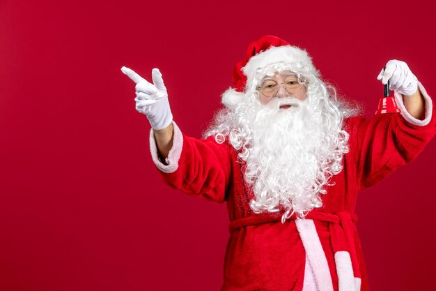 Vista frontal de santa claus sosteniendo una pequeña campana en regalo rojo emociones vacaciones de año nuevo de navidad