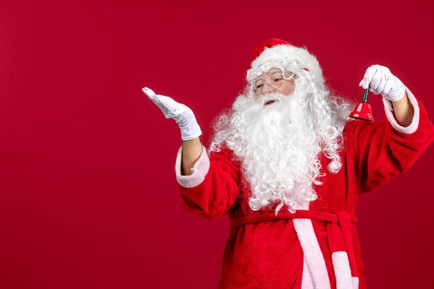 Vista frontal de santa claus sosteniendo una pequeña campana en vacaciones de navidad de emoción de regalo rojo