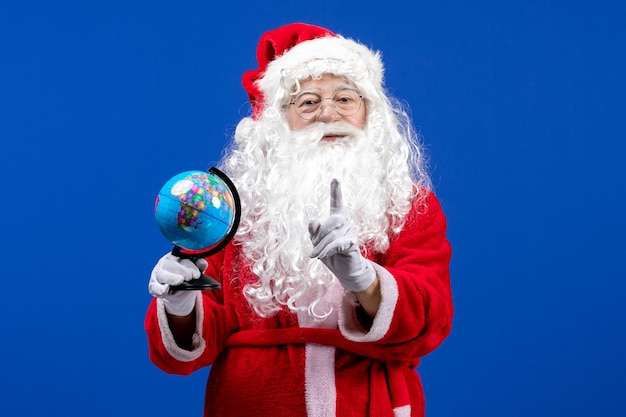 Vista frontal de santa claus sosteniendo un pequeño globo terráqueo en azul año nuevo color vacaciones navidad