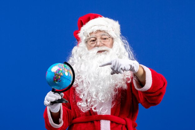 Vista frontal de santa claus sosteniendo un pequeño globo terráqueo en color azul año nuevo vacaciones de navidad