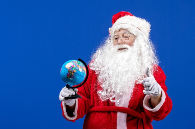 Vista frontal de santa claus sosteniendo un pequeño globo terráqueo en las vacaciones de navidad de color azul año nuevo