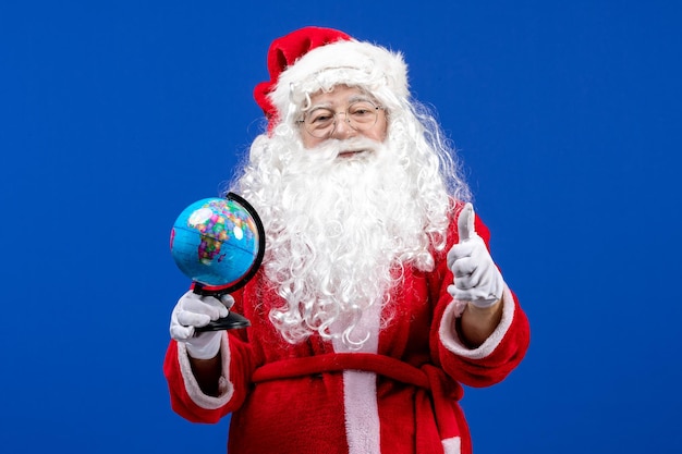 Vista frontal de santa claus sosteniendo un pequeño globo terráqueo en las vacaciones de navidad de color azul año nuevo