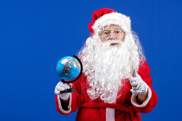 Vista frontal de santa claus sosteniendo un pequeño globo terráqueo en las vacaciones de navidad de color azul año nuevo