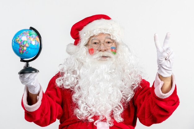 Vista frontal de santa claus sosteniendo un pequeño globo terráqueo vacaciones de navidad