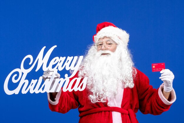 Vista frontal de santa claus con tarjeta bancaria y feliz navidad escribiendo en color azul regalo navideño navidad