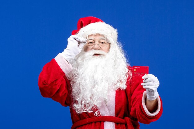 Vista frontal de santa claus con tarjeta bancaria roja en azul año nuevo color vacaciones navidad presente dinero