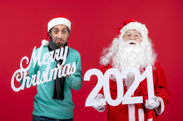 Vista frontal de santa claus con tenencia masculina y escritos de feliz navidad en color rojo navideño