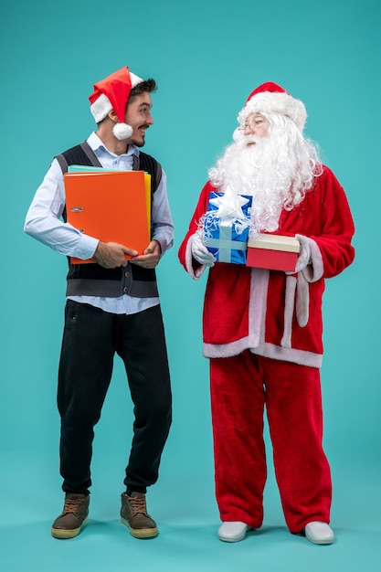 Vista frontal de santa claus con varones jóvenes y presenta sobre fondo azul.