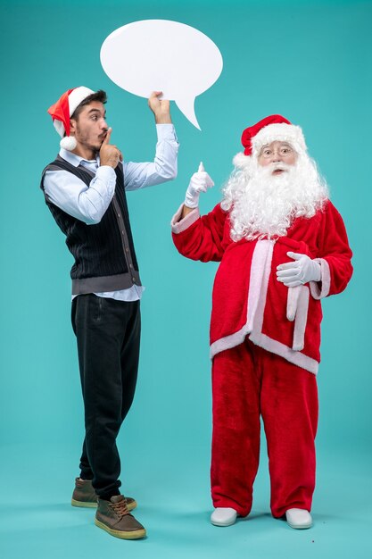 Vista frontal de santa claus con varones jóvenes que llevan a cabo cartel blanco sobre fondo azul.