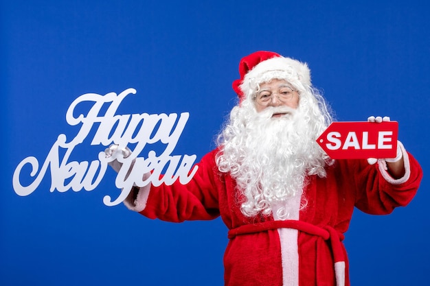 Foto gratuita vista frontal de santa claus con venta y feliz año nuevo escritos en color azul nieve vacaciones año nuevo