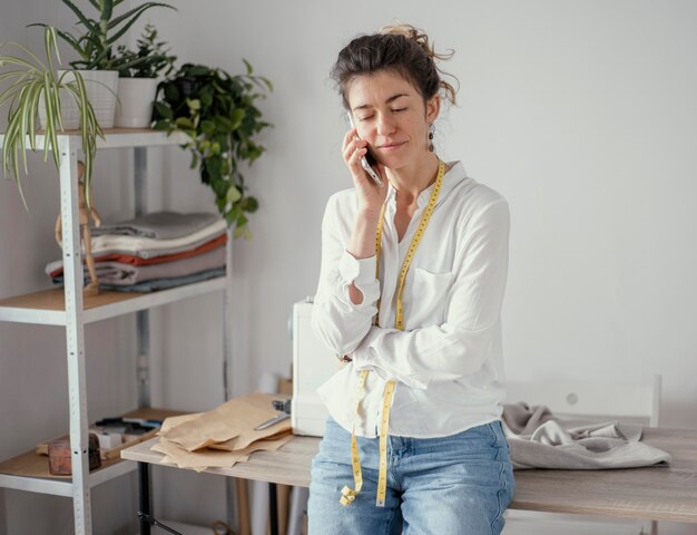Vista frontal del sastre femenino hablando por teléfono