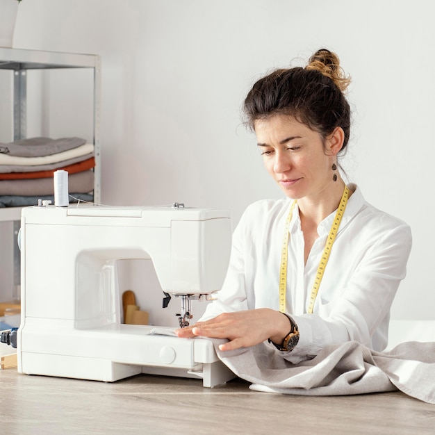 Vista frontal del sastre femenino trabajando con máquina de coser