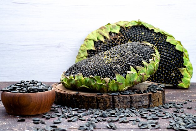 Una vista frontal de semillas de girasol negras frescas y sabrosas en el aceite de aperitivo de semillas de grano de escritorio marrón