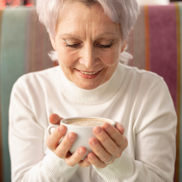 Vista frontal senior femenino sosteniendo una taza de café