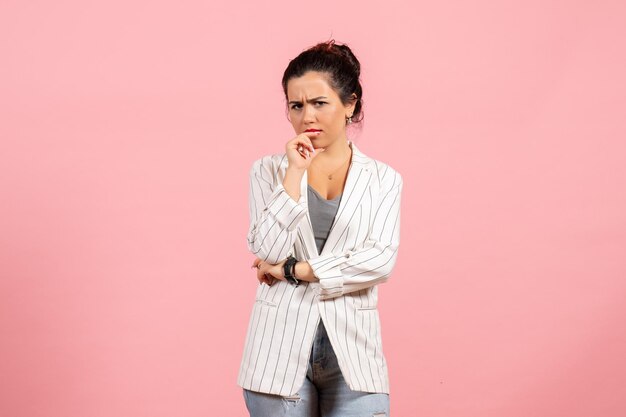 Vista frontal señorita en chaqueta blanca con cara de pensamiento sobre fondo rosa moda mujer emoción color sentimiento dama