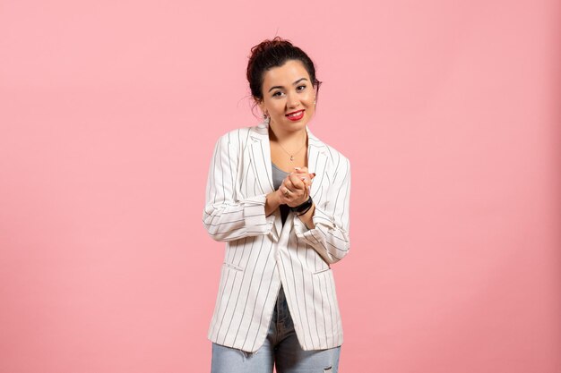 Vista frontal señorita con chaqueta blanca sonriendo sobre fondo rosa moda mujer emoción color sentimiento dama